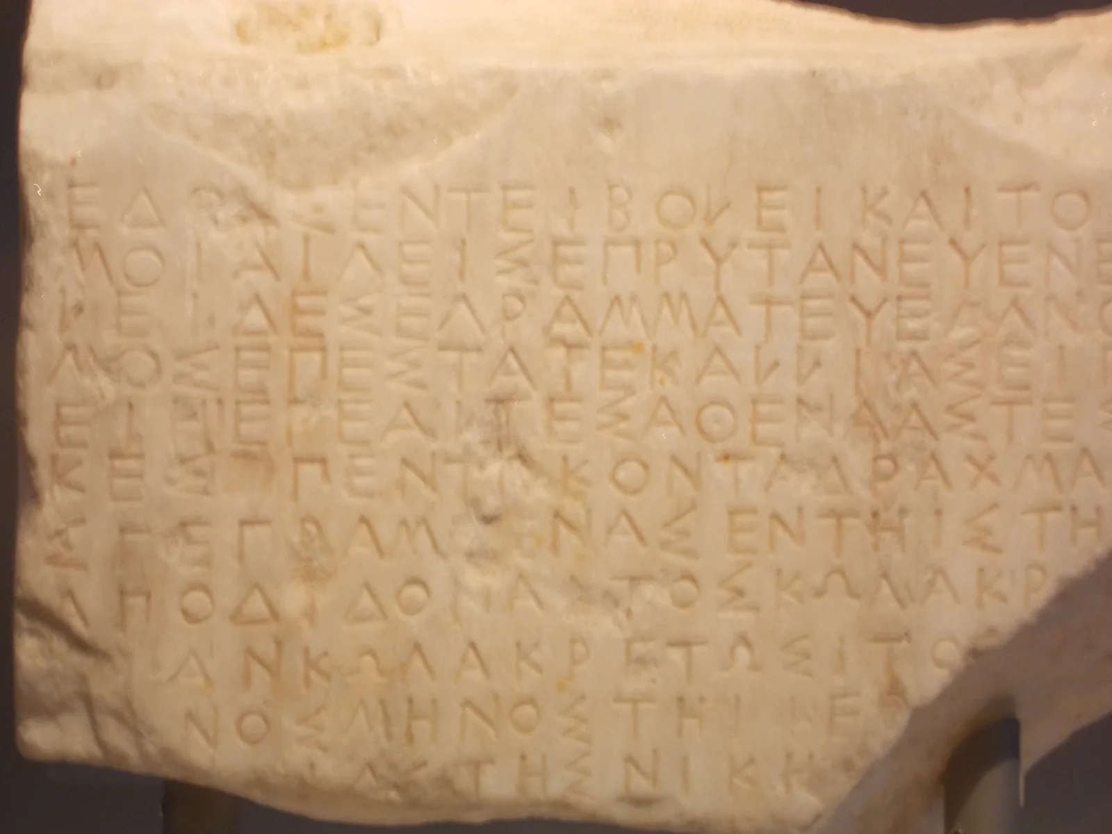 Ancient marble slab with carved Greek inscription showing clearly visible Greek letters.