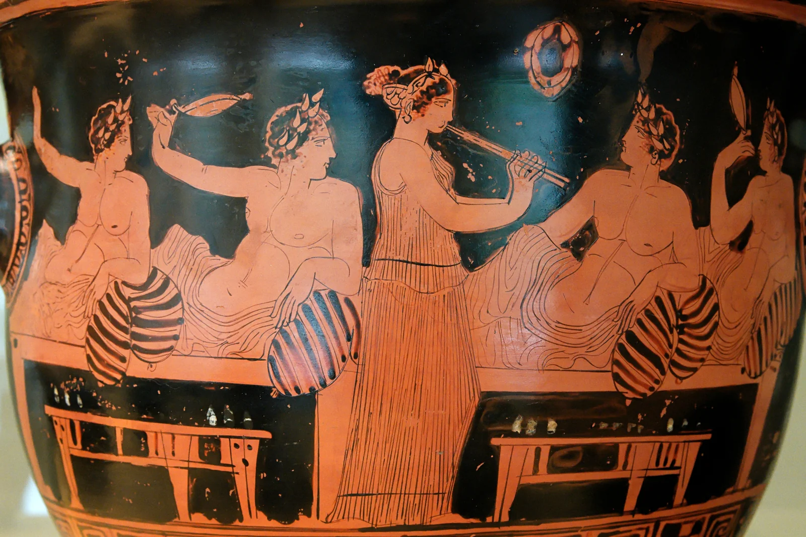 Ancient Greek red-figure pottery showing a symposium scene with figures in conversation, painted by the Nicias Painter.